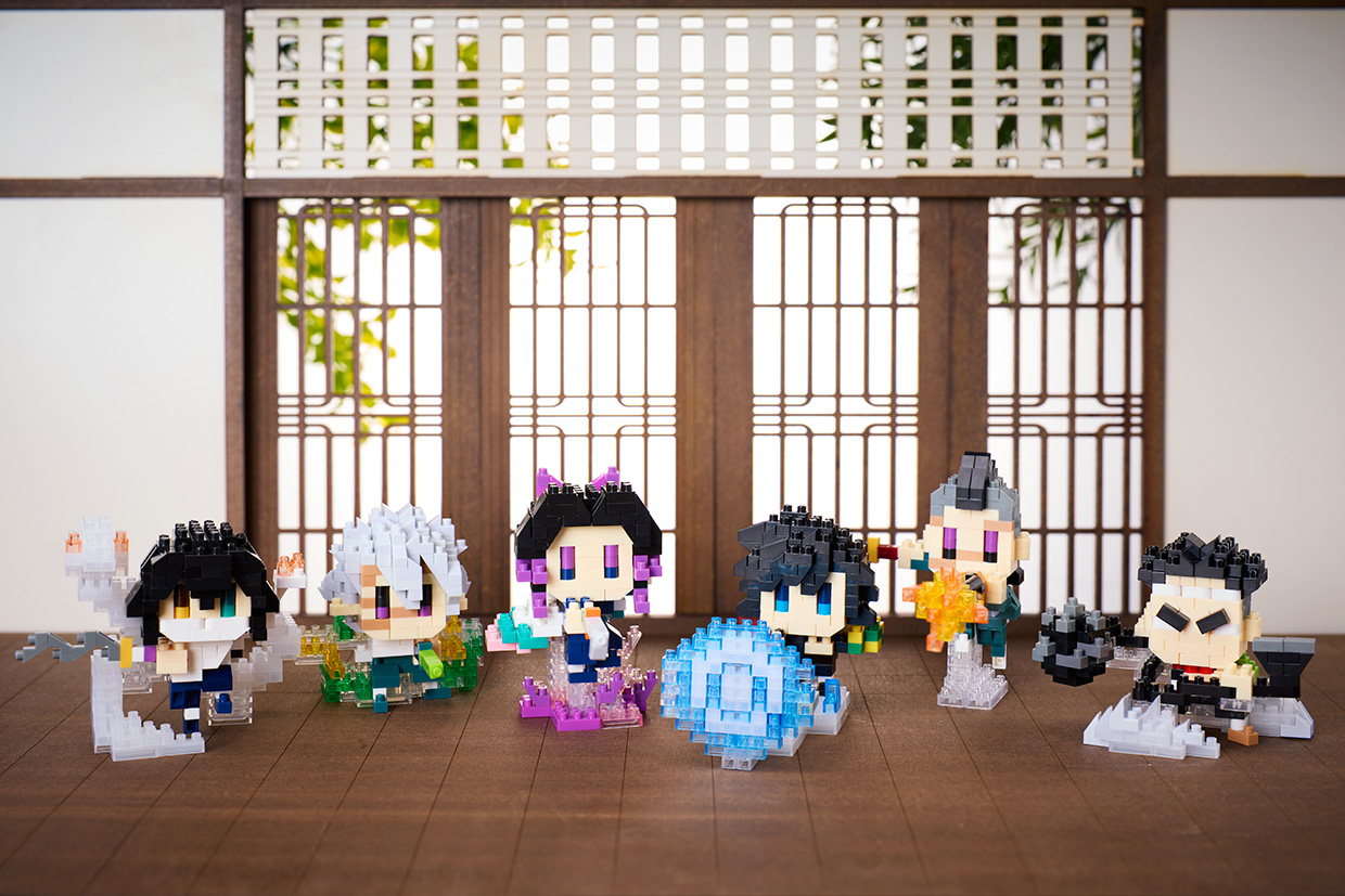 Six nanoblock Demon Slayer figures with clear blue, purple and orange effect pieces displayed in front of a wooden screen