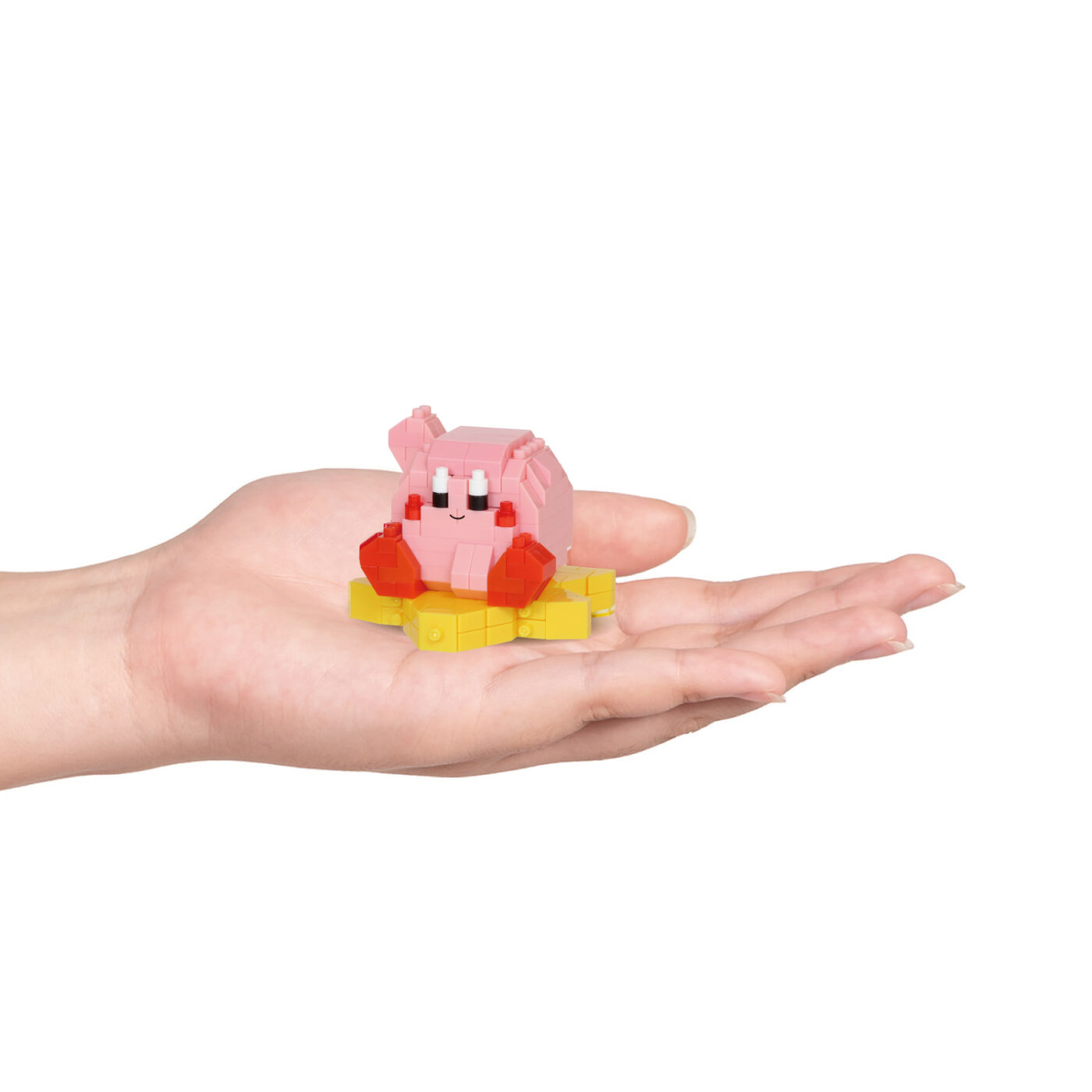 Assembled Kirby nanoblock model on a Warp Star resting in an open palm to show scale
