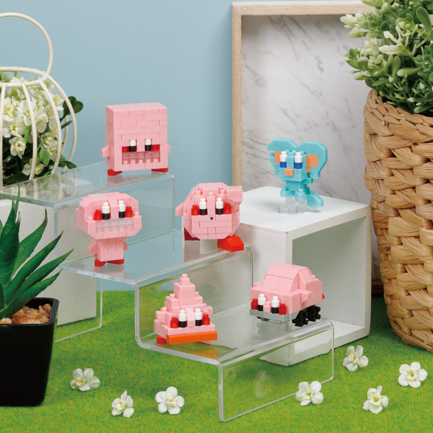 Small mininano Kirby figures arranged on a tiered display stand beside plants