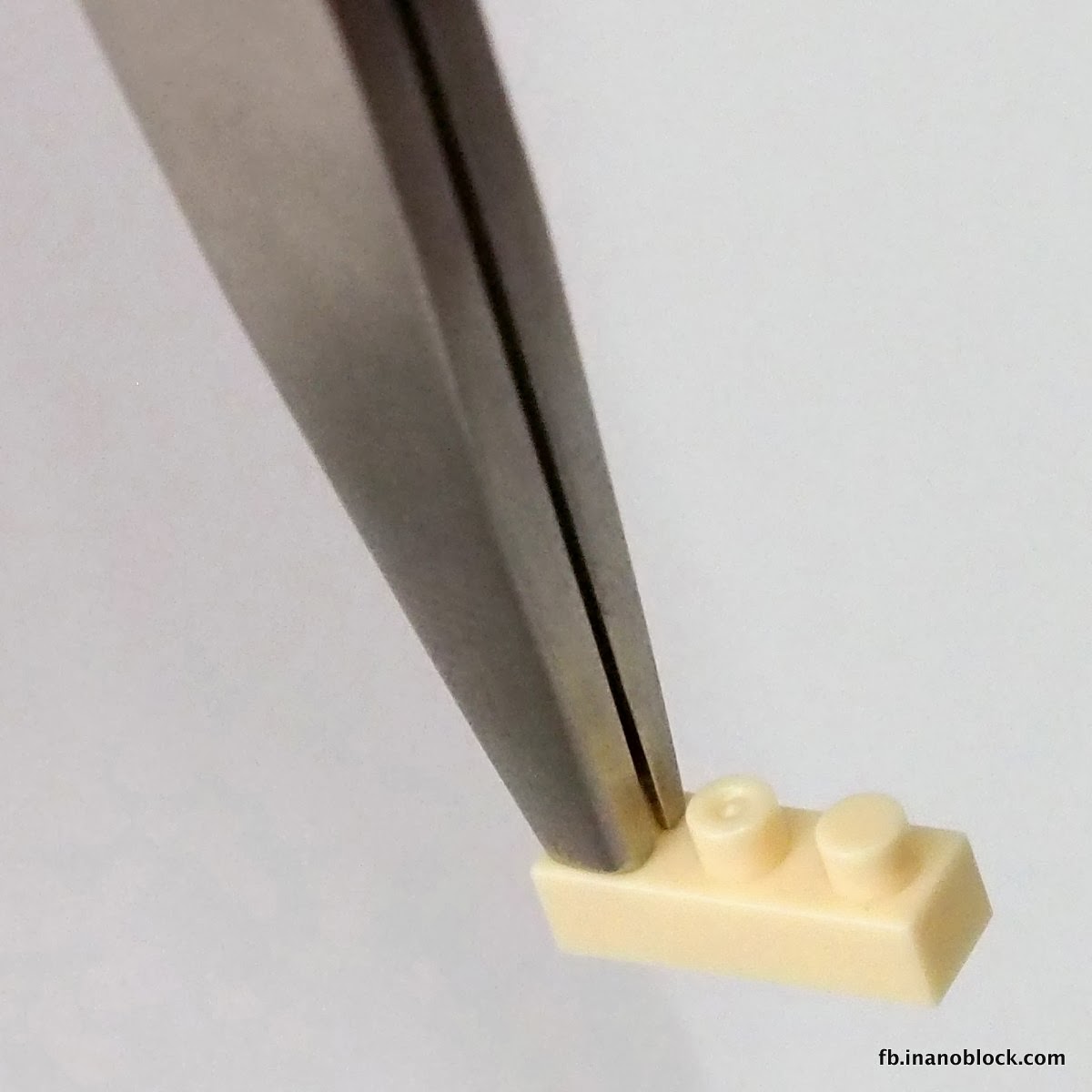 NB-019 tweezers gripping a flat tan nanoblock tile by its edge