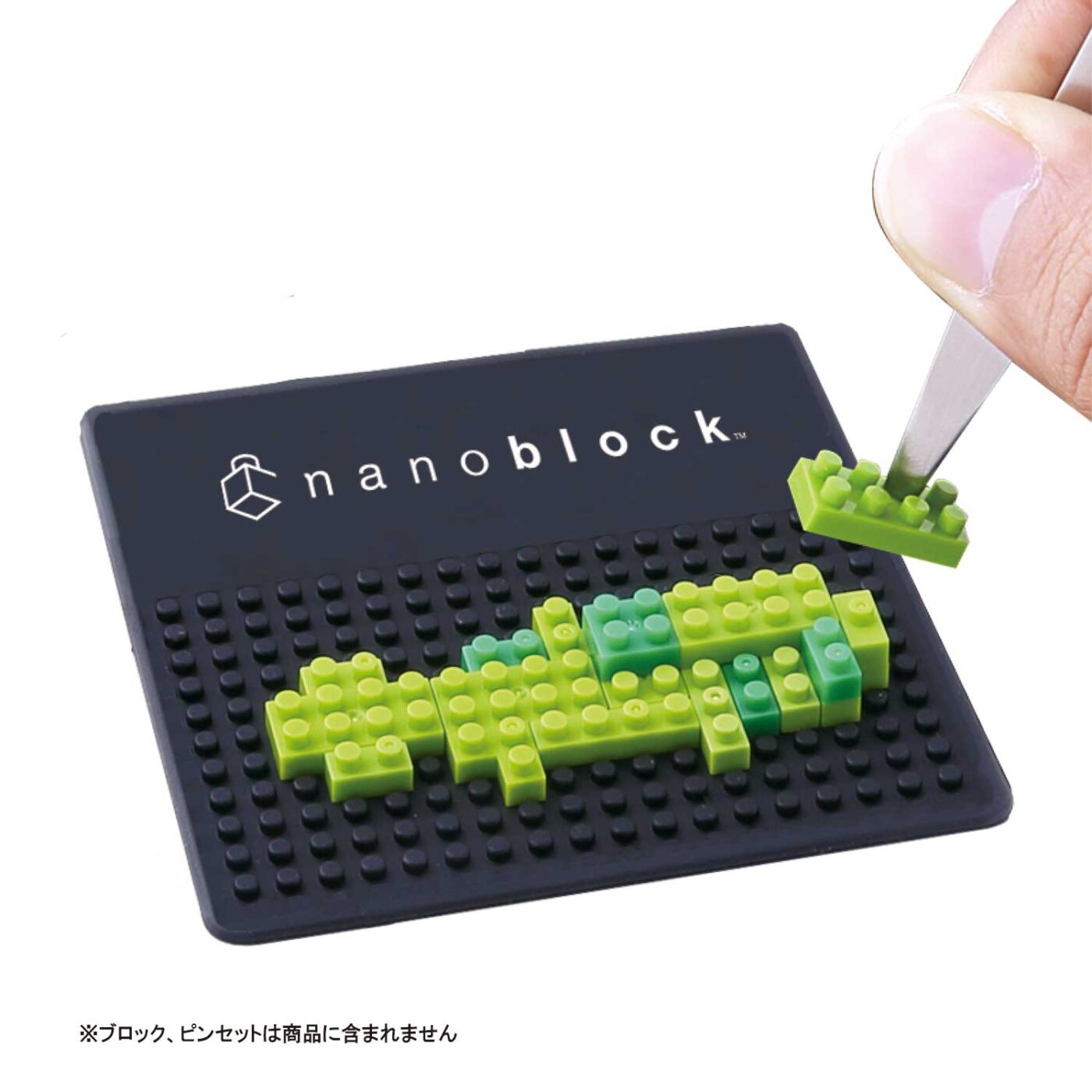 Green nanoblock model on a nanoblock PAD mini while a hand places a brick with tweezers