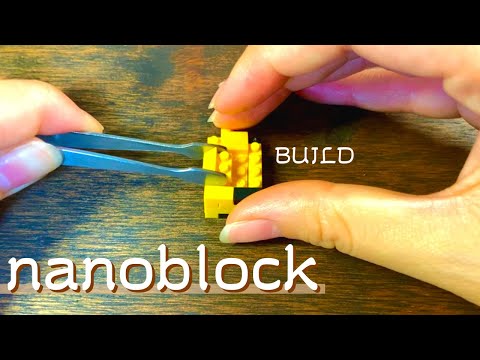 Builder using tweezers while assembling the yellow NBMC-41 Giraffe Nanoblock model